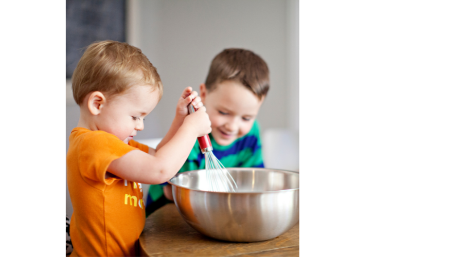 two kids stirring in a silver bowl