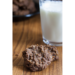 two chocolate oatmeal cookies sitting on a wooden table with glass of milk