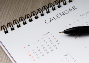 spiral bound calendar laying on wood with pen